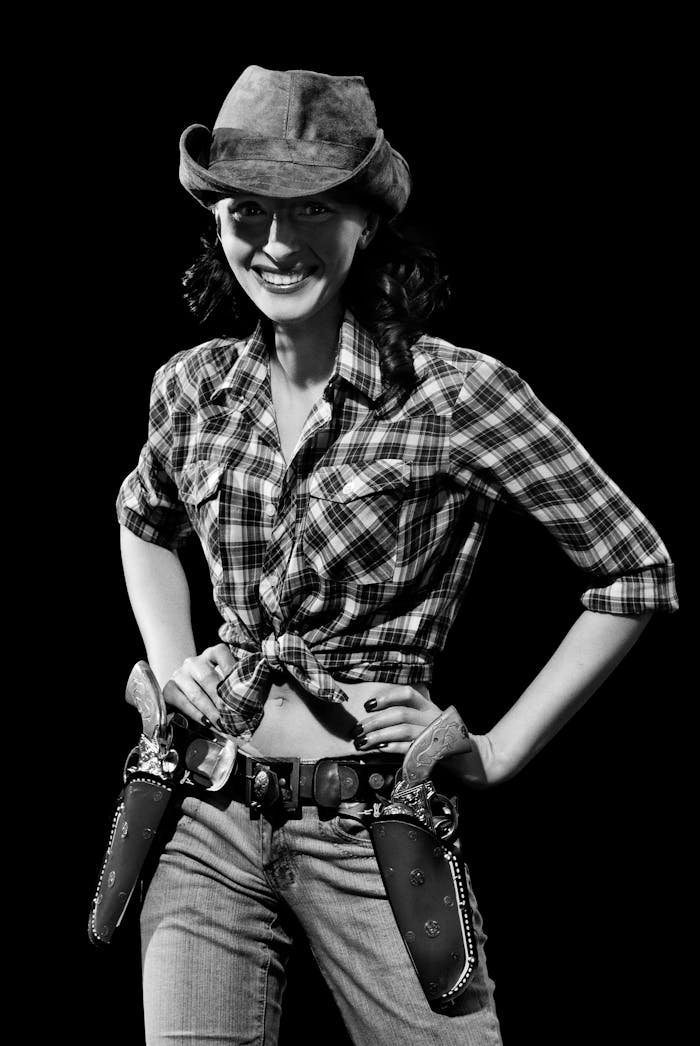 digital Black and white portrait of a smiling cowgirl in a plaid shirt and hat.